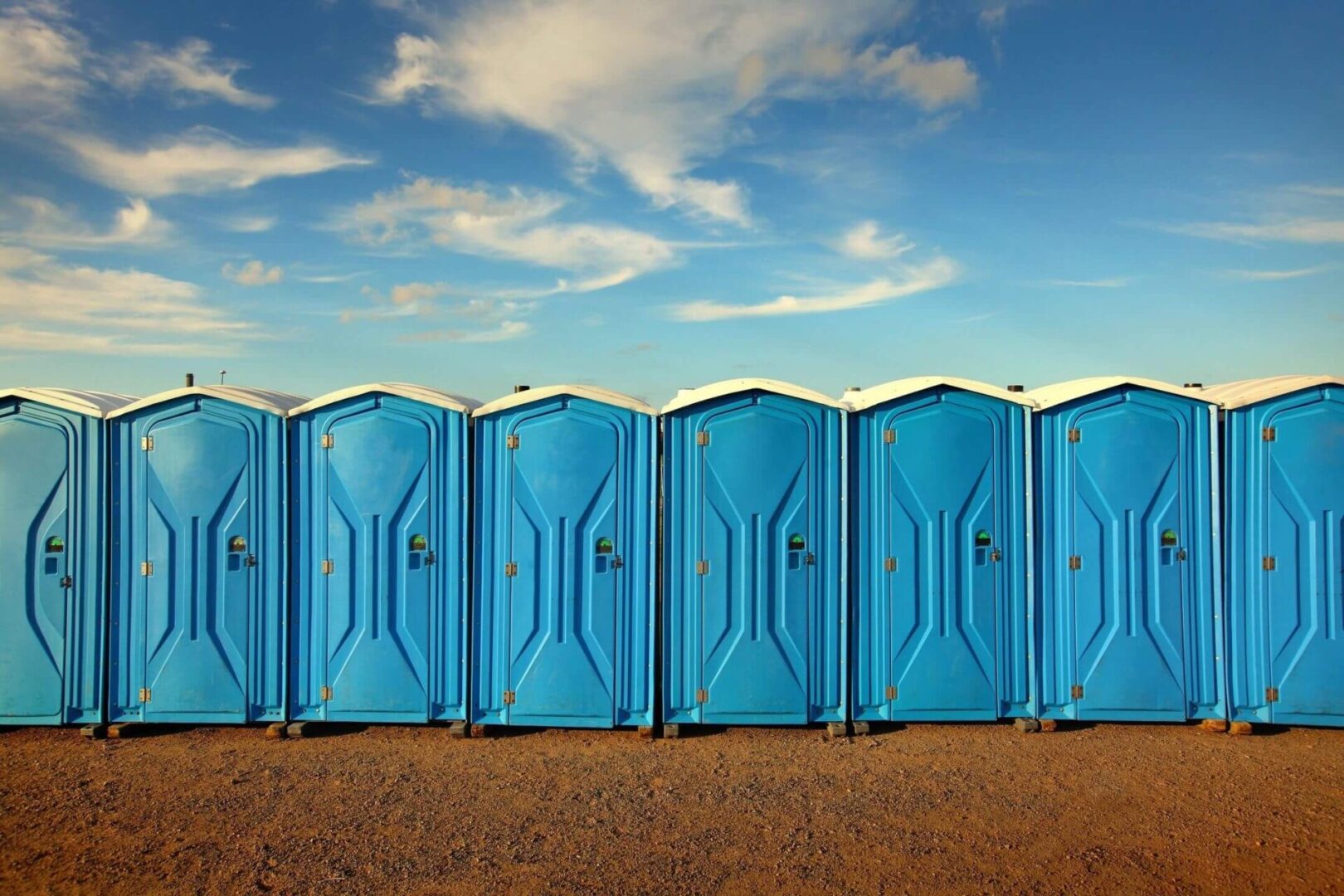 A row of portable toilets on the side of a road.