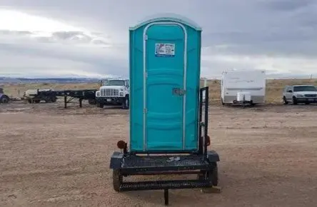 A blue portable toilet sitting on top of a trailer.